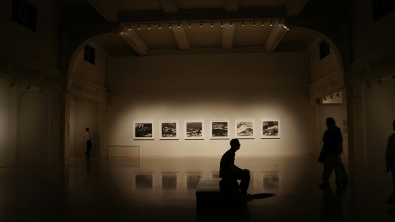 Man sitting in a dimly lit gallery. Photo by Pexels/Pixabay